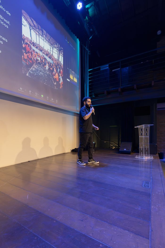 Man giving a presentation on stage with a digital screen in a modern venue.
